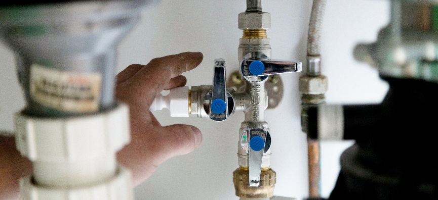 Under kitchen sink image of hand reaching for Zetco 3-way manifold